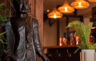 Nusara Thai restaurant with a thai statue and warm lighting and plants