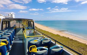 A sunny view of Bournemouth beach and blue sea from open top yellow bus