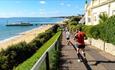 People running down cliff top towards pier with a blue sky