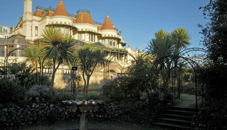 The Russell-Cotes Art Gallery & Museum Victorian villa in the background set against blue sky, with a fountain and trees in the foreground