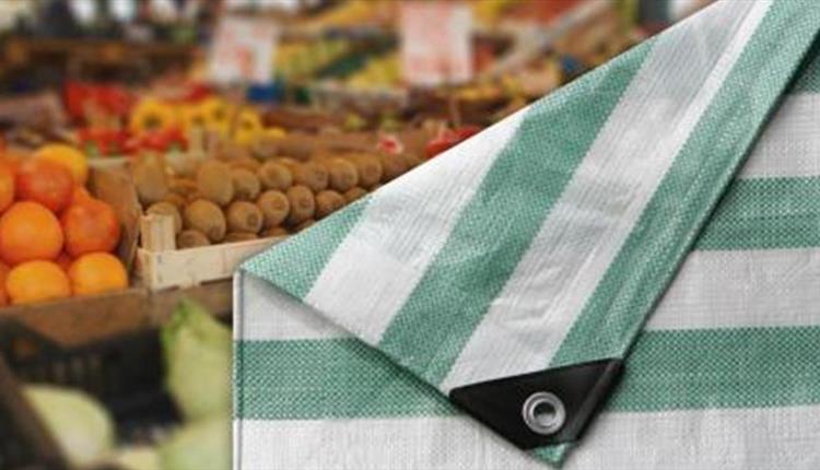 Folded market tarpaulin with fresh fruit and veg in background.