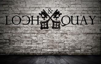 loch and quay logo superimposed on a white brick wall.