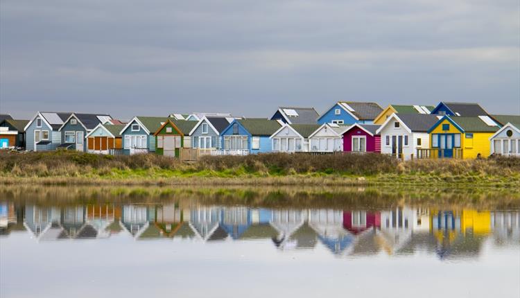 Colourful Mudeford beach huts in a row.