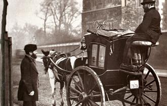 old time photograph of one man on a horse and buggy and another man standing in the street