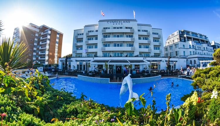 Image of the exterior of Cumberland Hotel featuring its well kept pool and sculptures